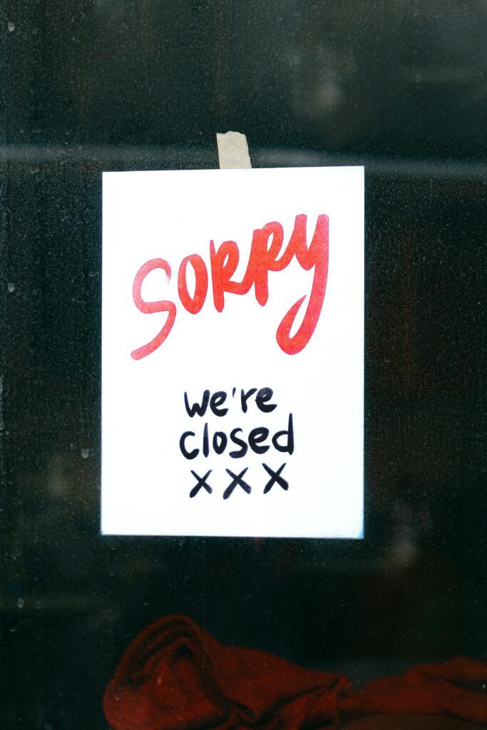 Close-up of a handwritten 'Sorry we're closed' sign taped to a window, conveying closure.